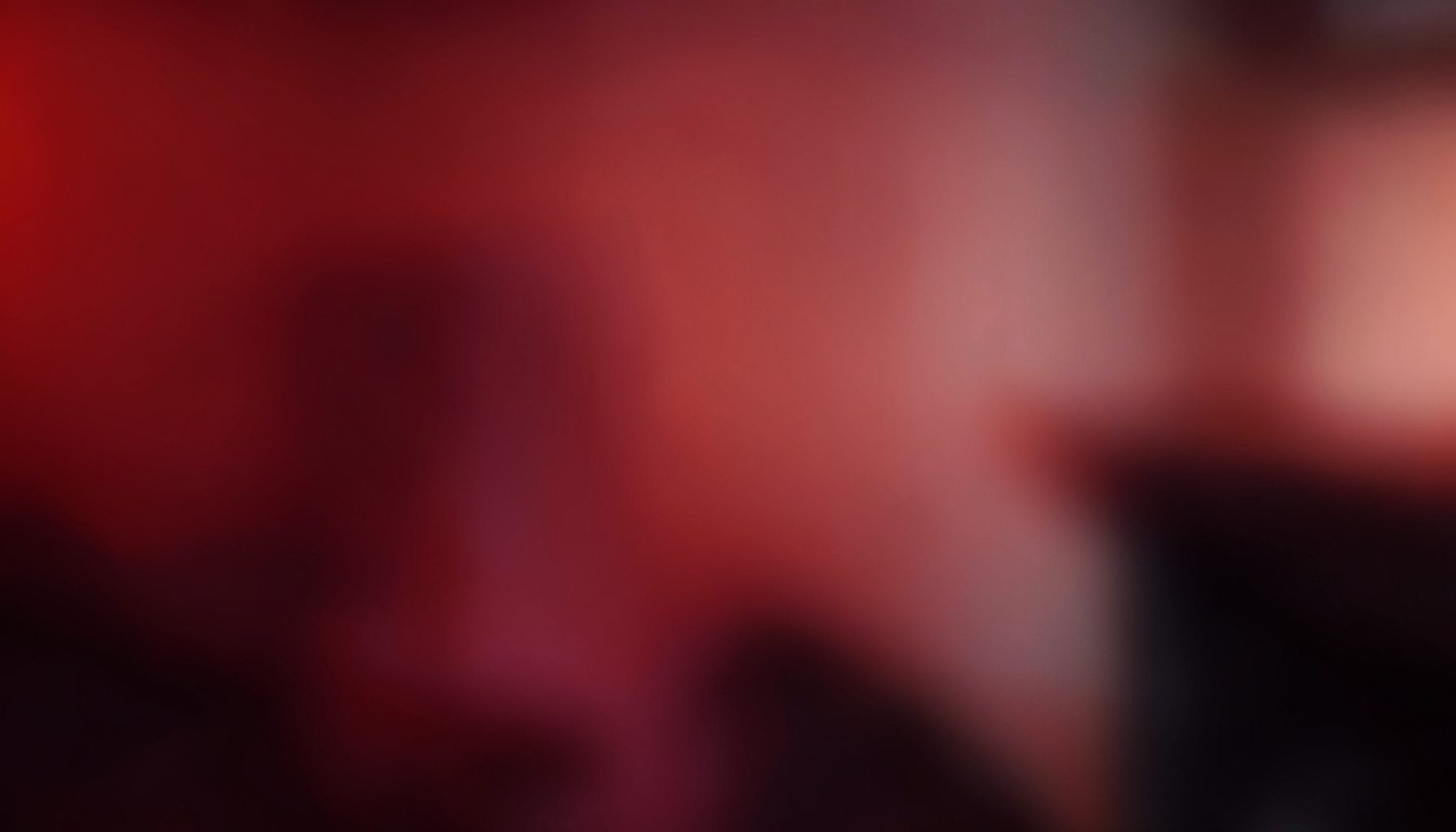 Abstract warm gradient with deep red and dark tones, soft blurred shapes suggesting a modern digital workspace